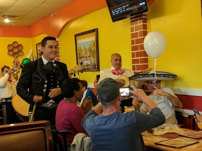 A man is taking a picture of a mariachi band in a restaurant.