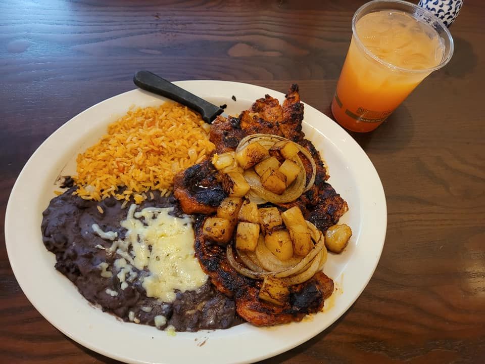 A plate of food with beans, rice and a drink on a table.