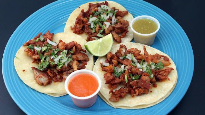 A blue plate topped with three tacos and two dipping sauces.