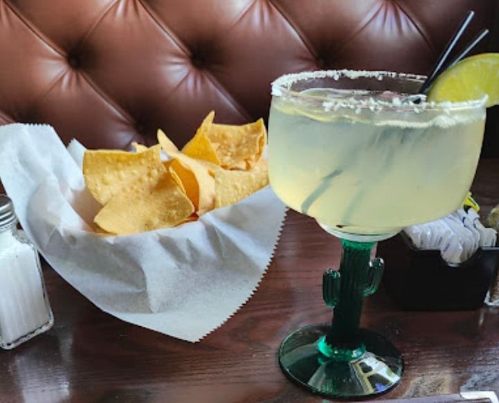 A bowl of tortilla chips and a margarita on a table