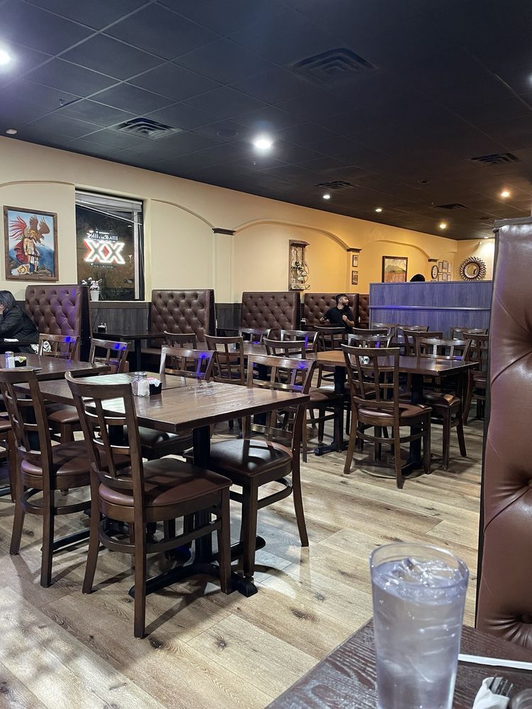 A restaurant with tables and chairs and a glass of water on a table.
