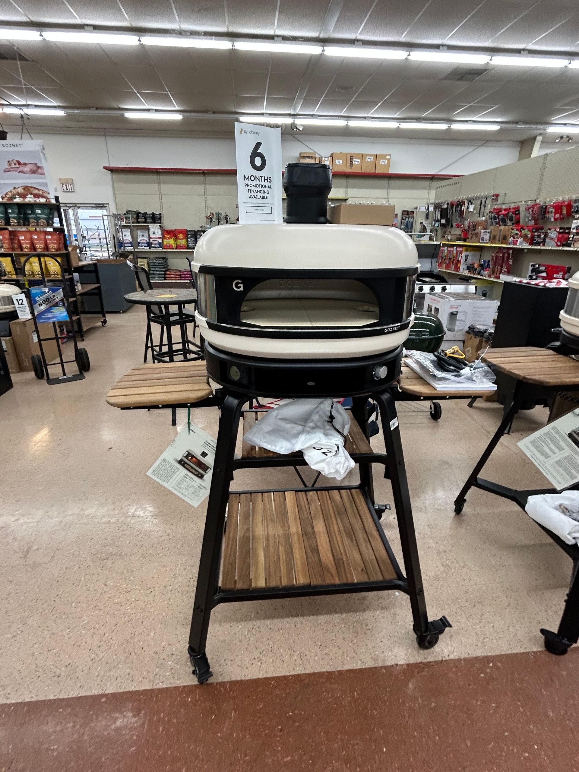 A pizza oven is sitting on a stand in a store.