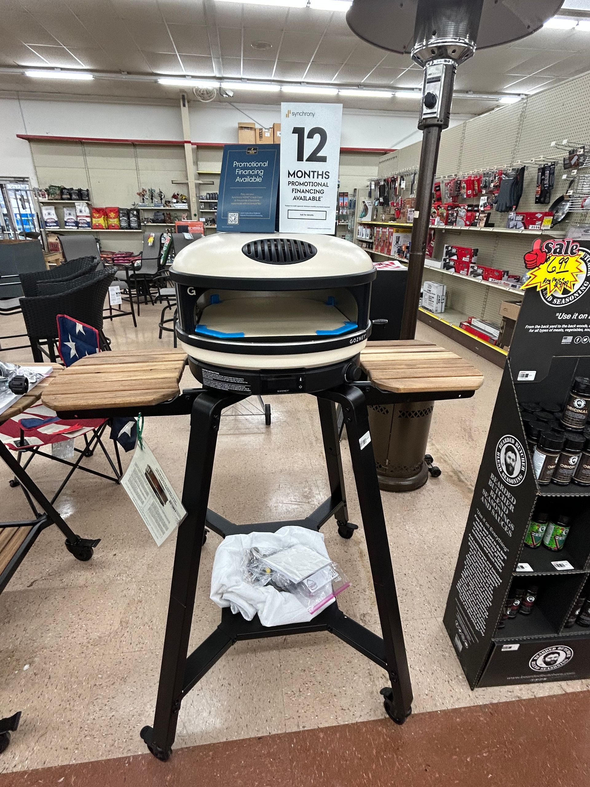 A pizza oven is sitting on top of a wooden stand in a store.