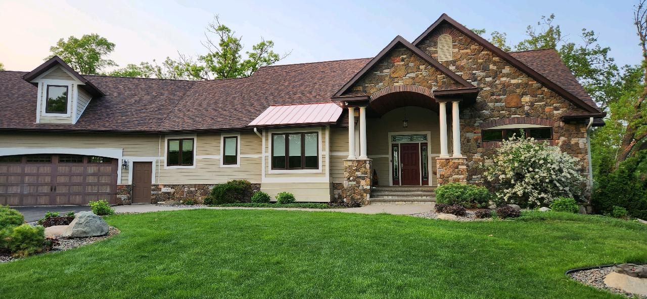 A house with a stone facade and a green lawn.