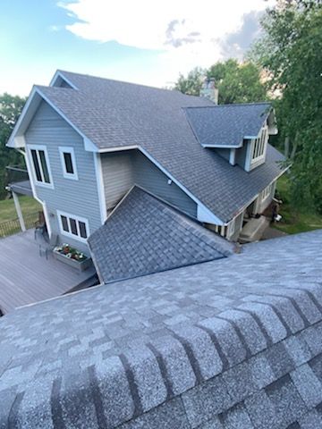 Blue-gray house with a multi-level roof and a wooden deck, viewed from above.