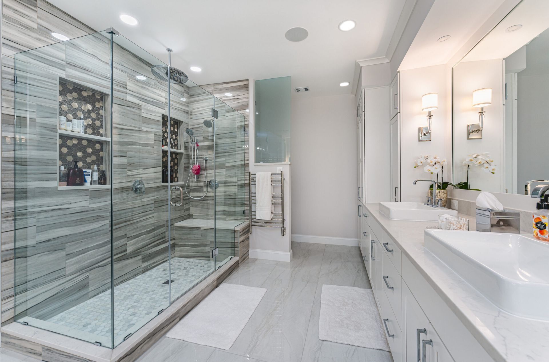 Modern bathroom with glass shower, double vanity, and white-and-gray tile