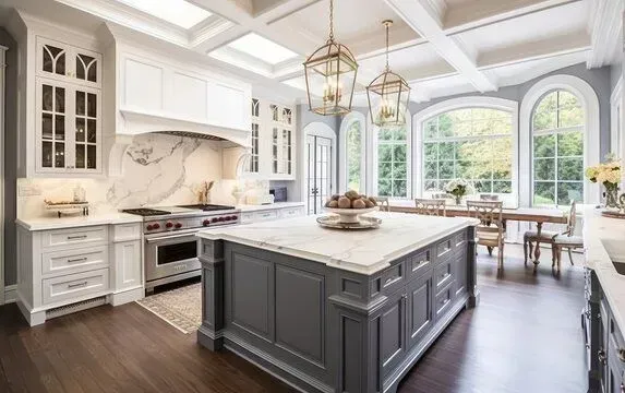 Bright luxury kitchen with white cabinets, gray island, marble backsplash, and large arched windows
