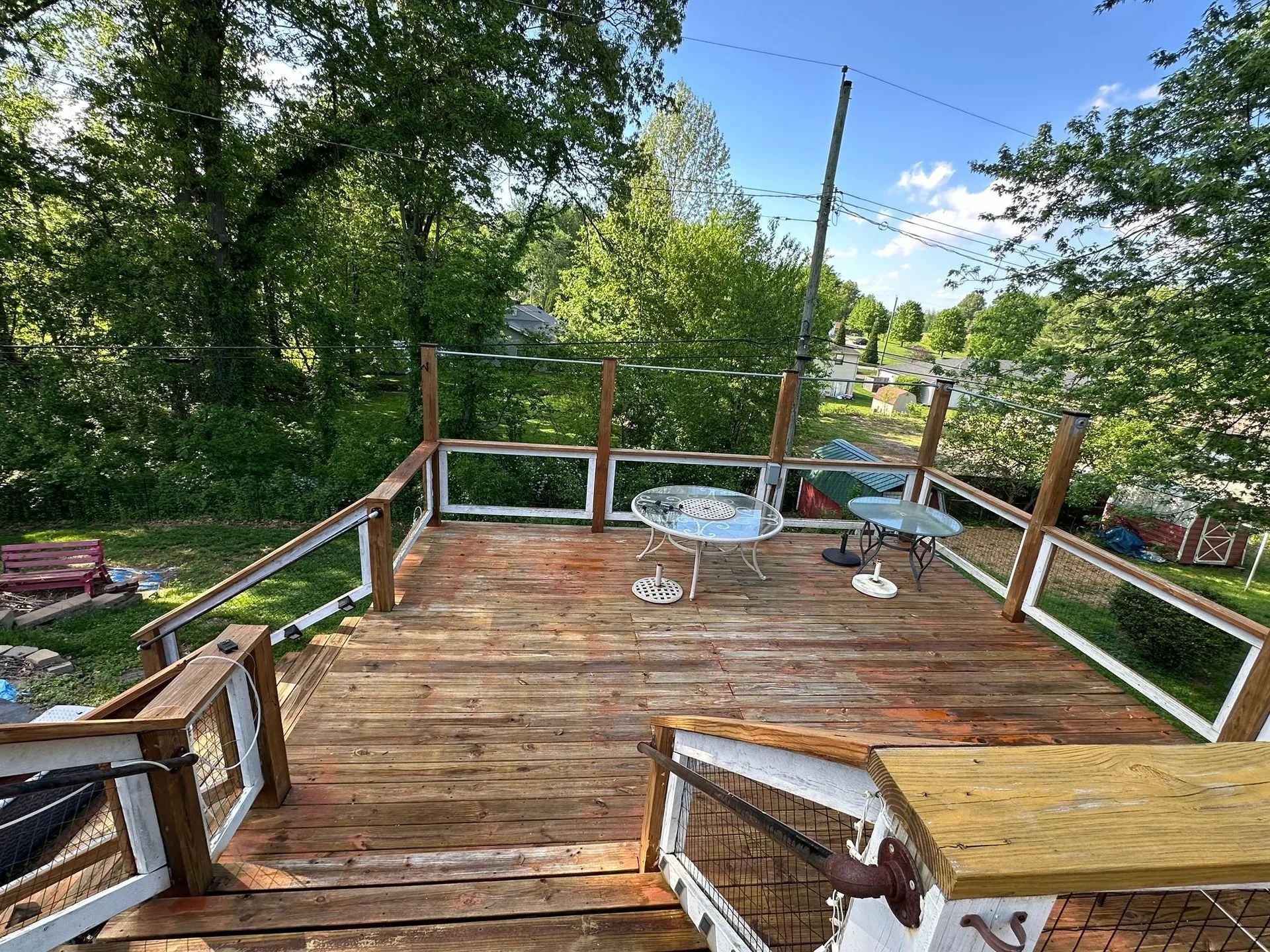 Wooden deck with white railings, a small table and chairs, and a natural setting.