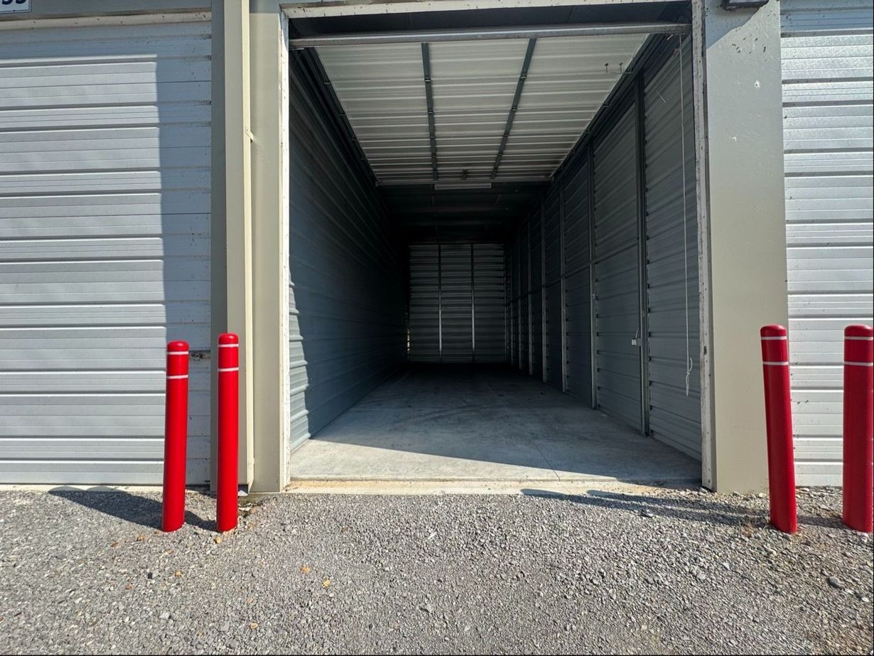 Open storage unit with bright red posts, gravel, and dim interior.