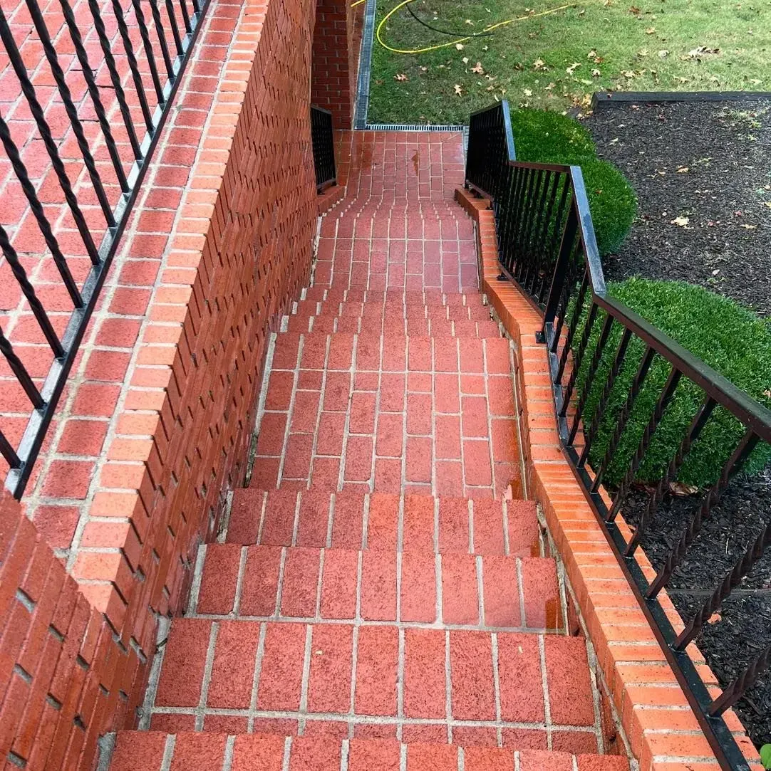 Red pickup truck parked on lawn next to concrete walkway leading to a house. Large rock near porch.