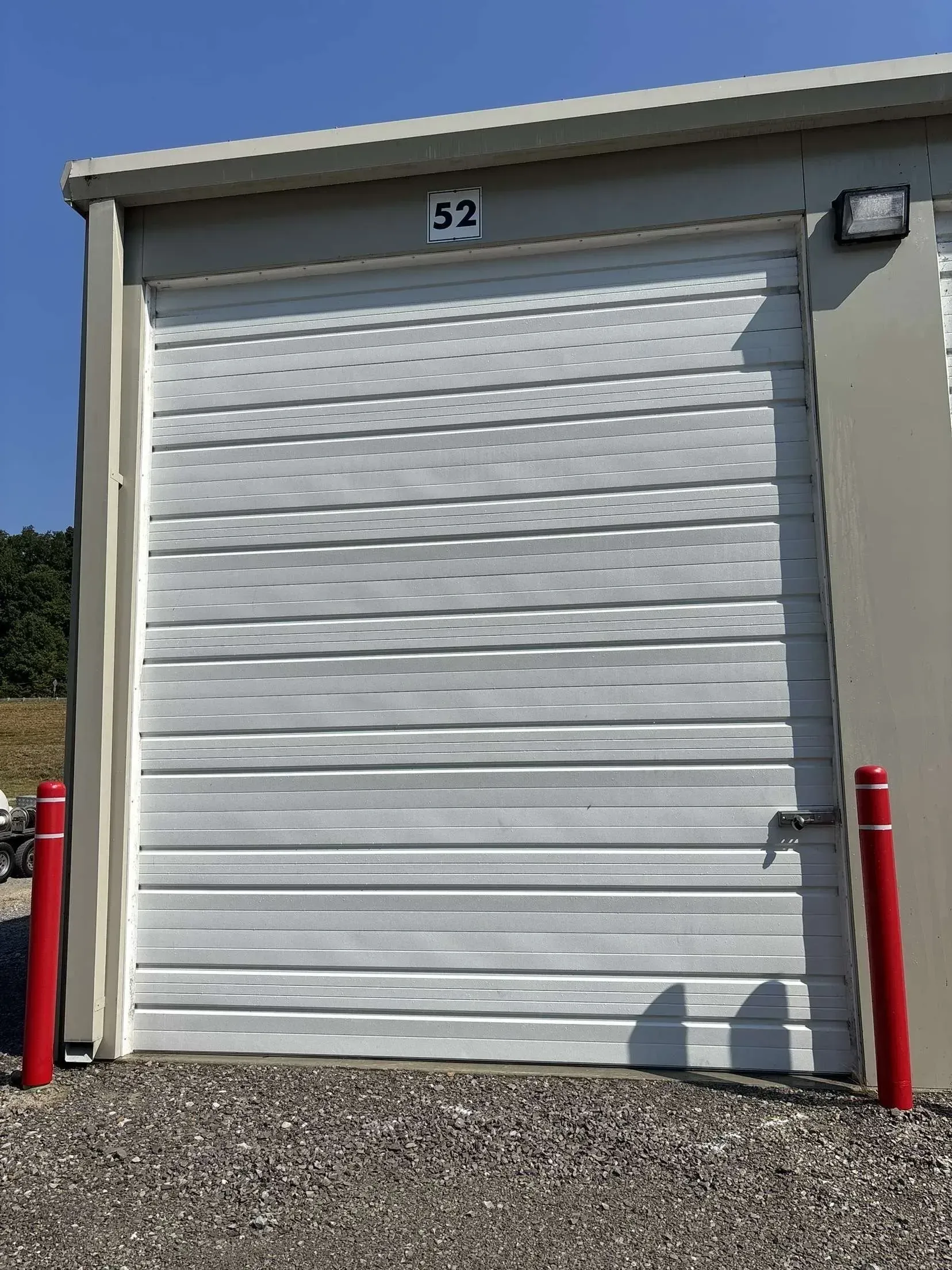 White storage unit door with the number 52. Red posts flank the door.