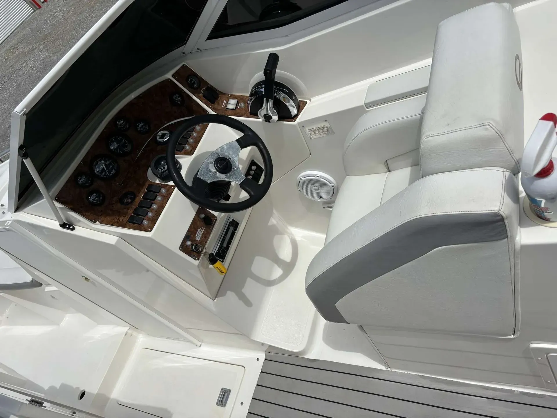 Boat interior with steering wheel, gauges, and captain's chair, white and brown.