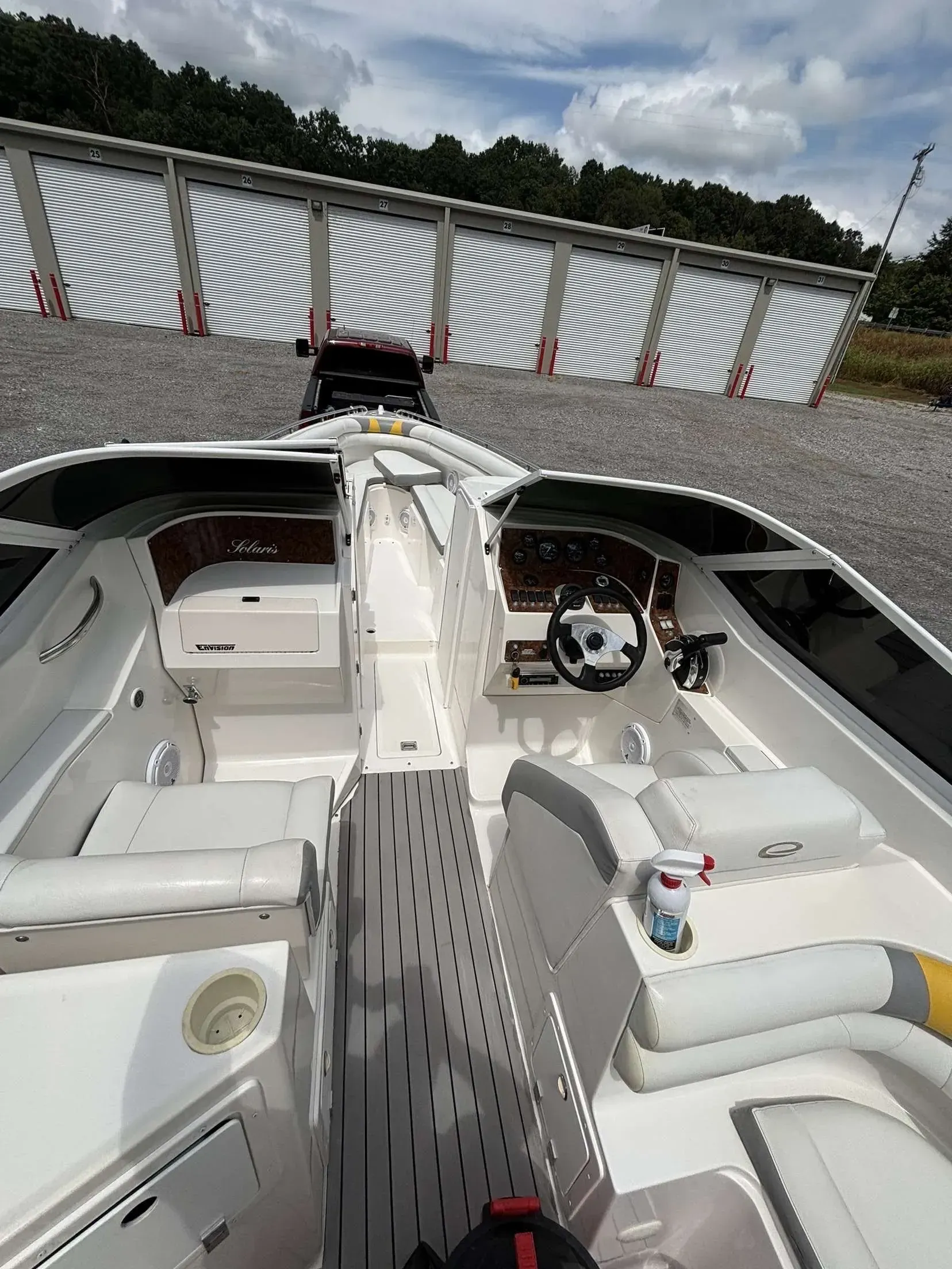 White speed boat interior with steering wheel, seats, and a corrugated metal structure in the background.