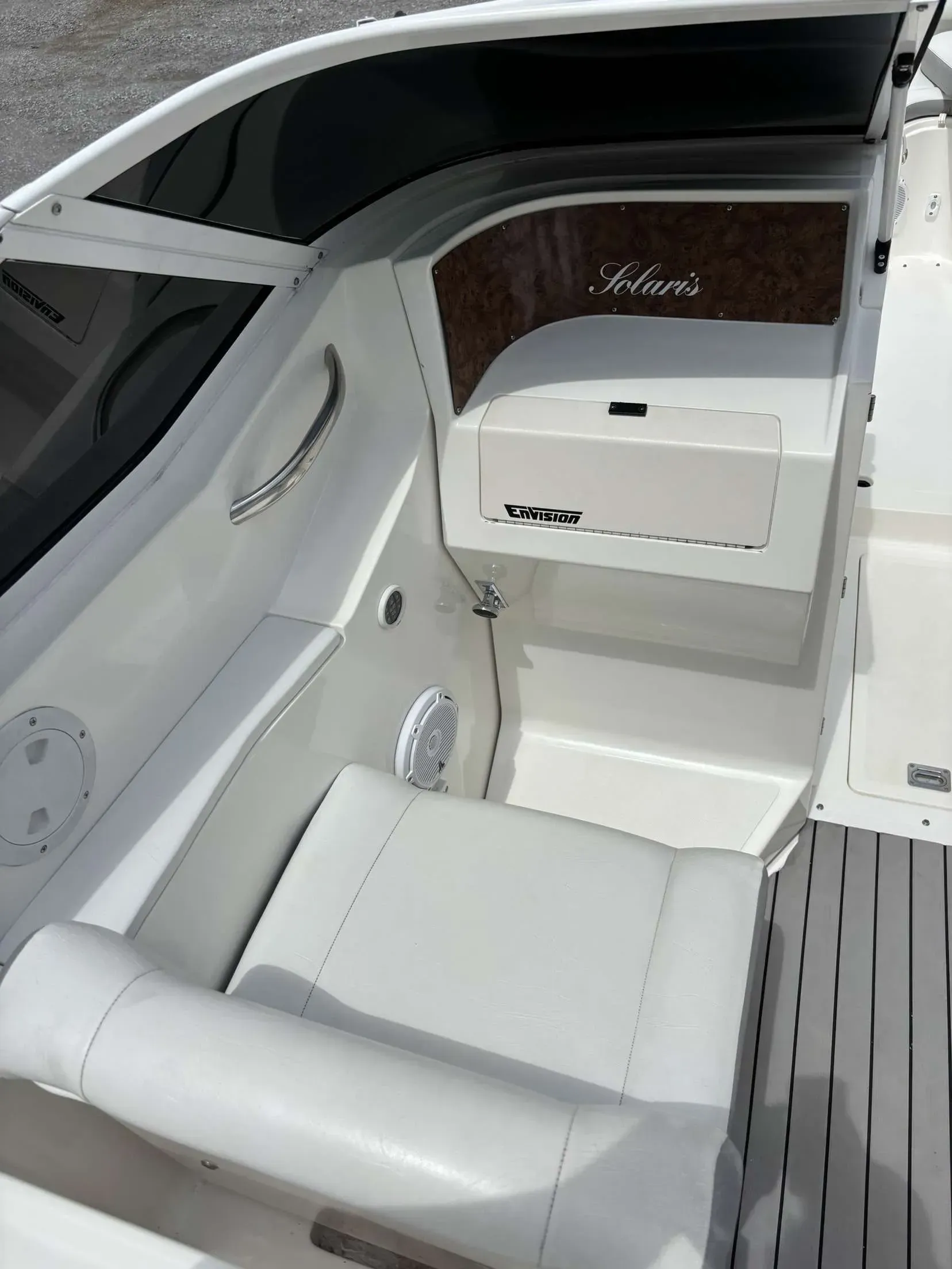 Interior of a white boat with seating, storage, and a dark tinted windshield.