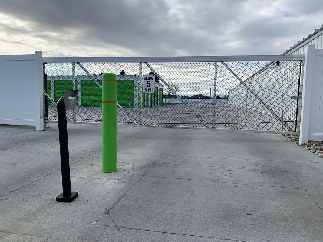 A green pole is in front of a chain link fence.