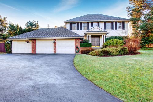 Suburban two-story house with three-car garage, driveway, and landscaped front lawn