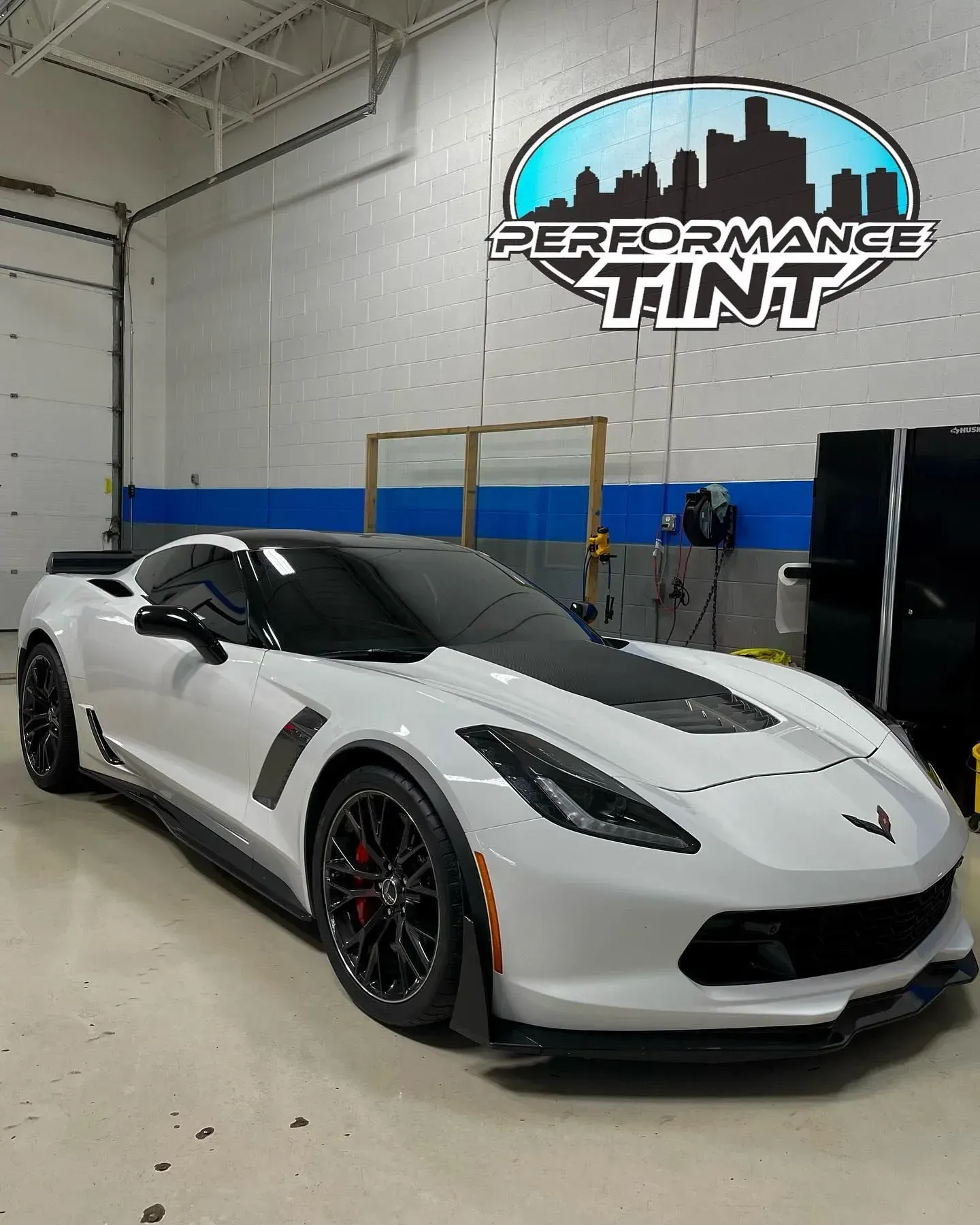 White Chevrolet Corvette in a garage with a Performance Tint sign on the wall