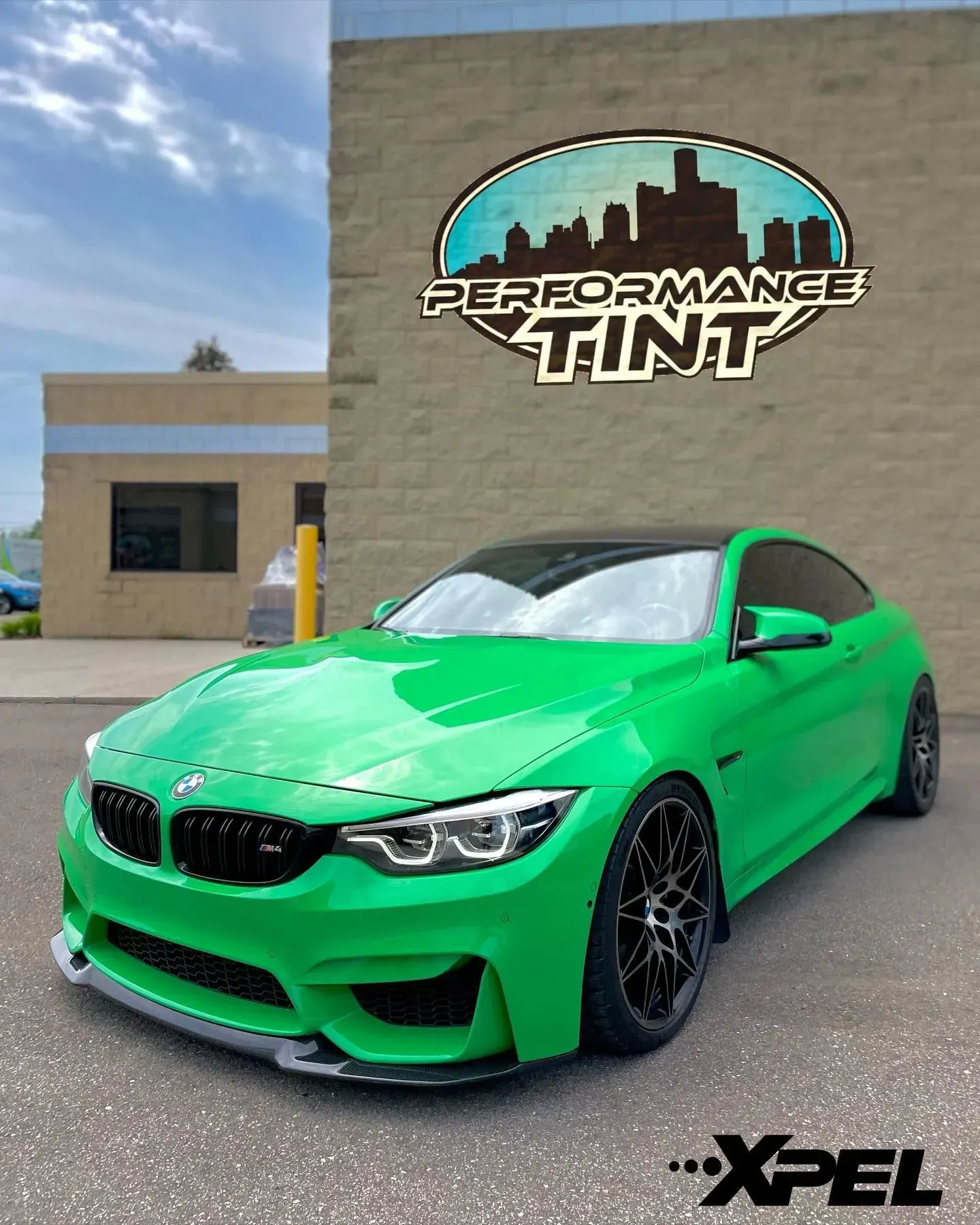 Bright green BMW coupe parked outside a Speedformance Tint shop, with XPEL logo on the wall