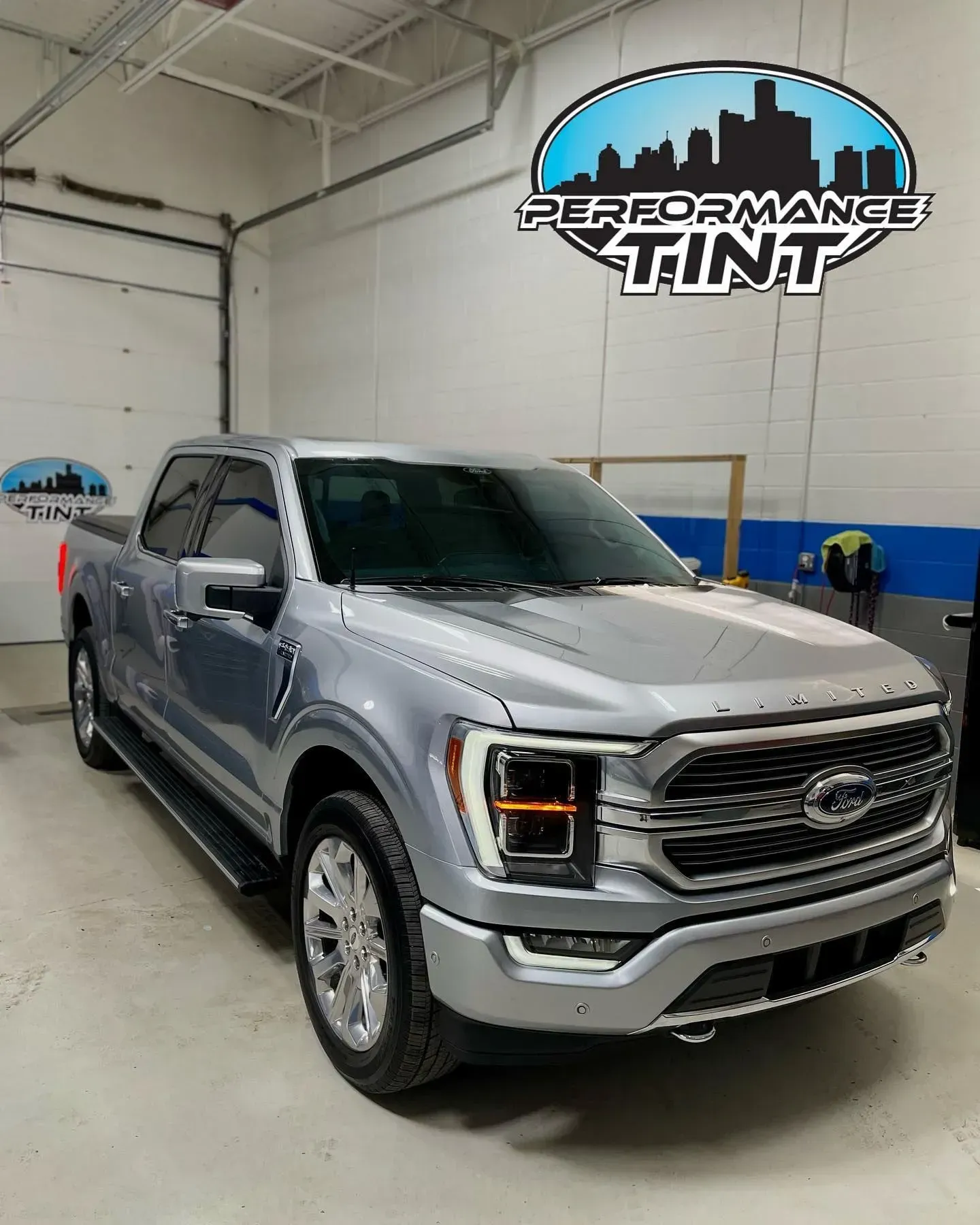 Silver Ford F-150 truck inside an auto shop under a Performance Tint sign