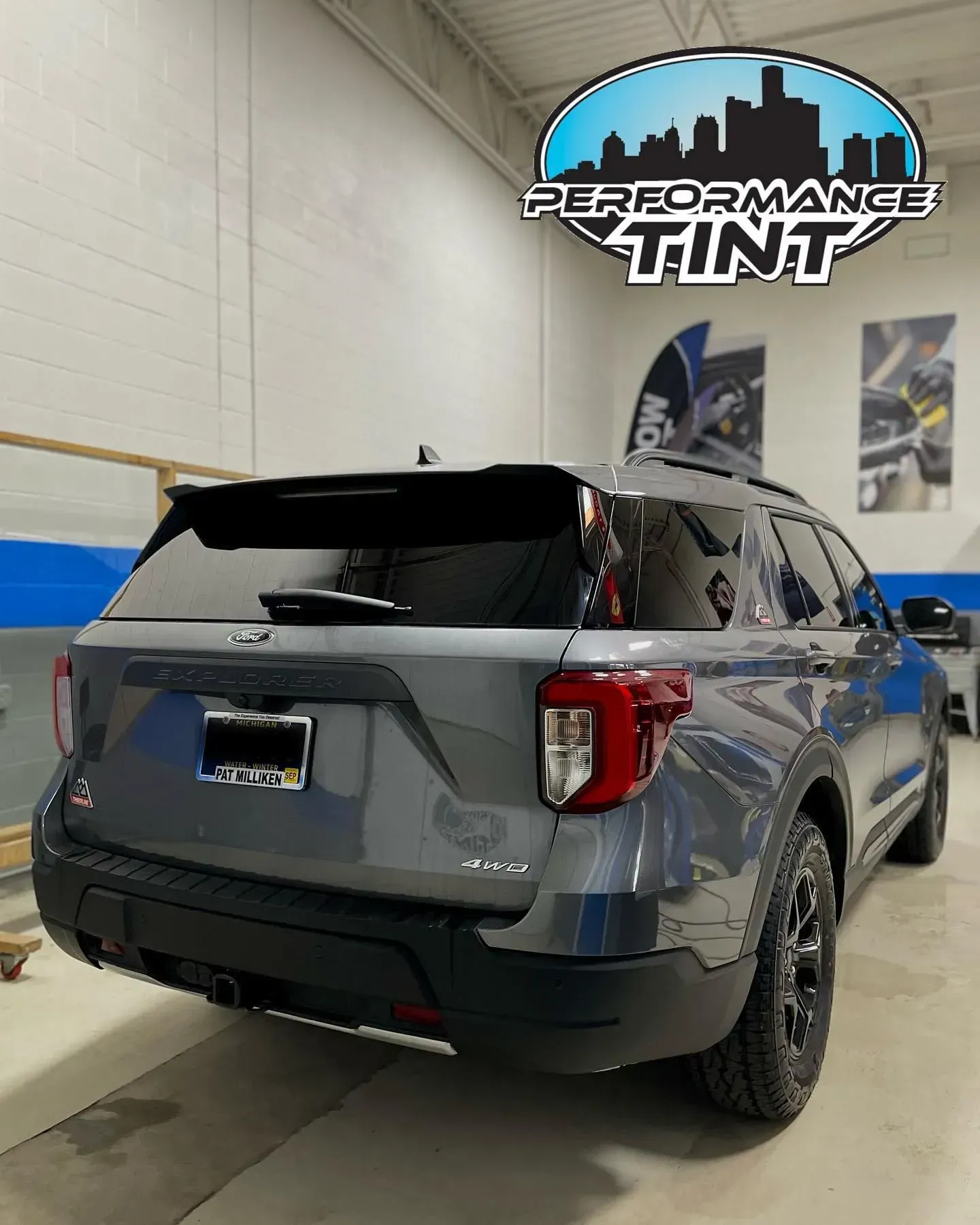 Gray SUV parked inside a tint shop beneath a “Performance Tint” sign