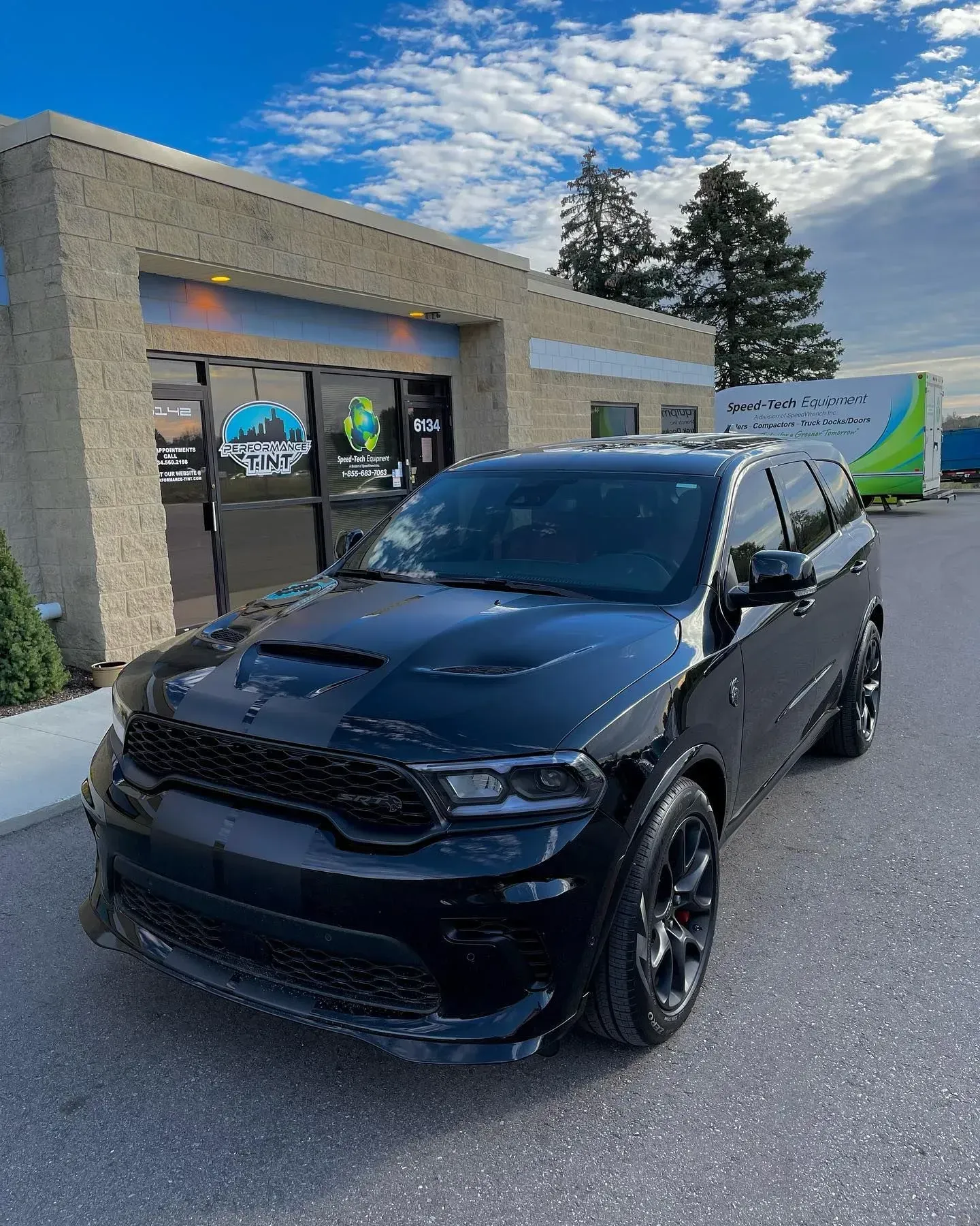 Black SUV parked outside a building under a blue sky, front view