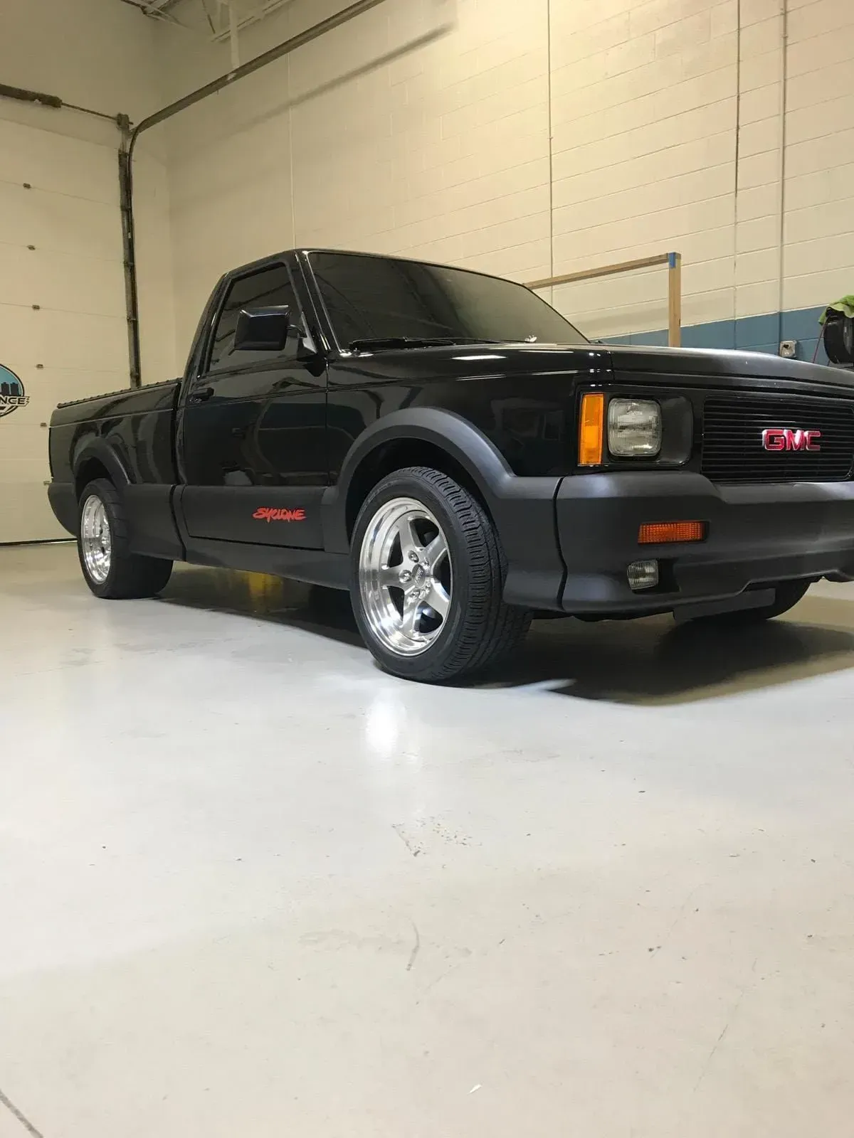 Black GMC pickup truck in a garage, front-left view