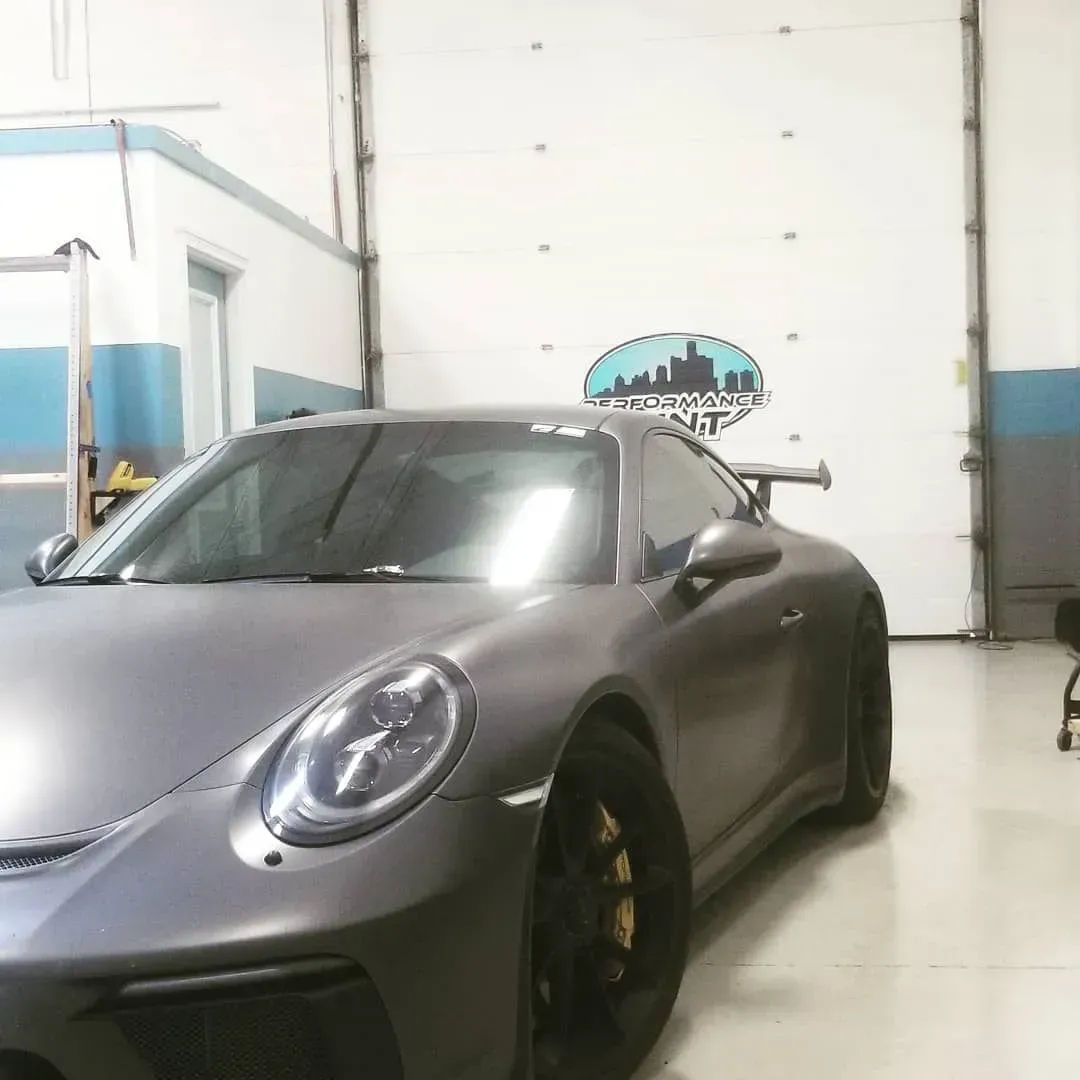 Silver sports car parked inside a clean garage with white walls and blue trim