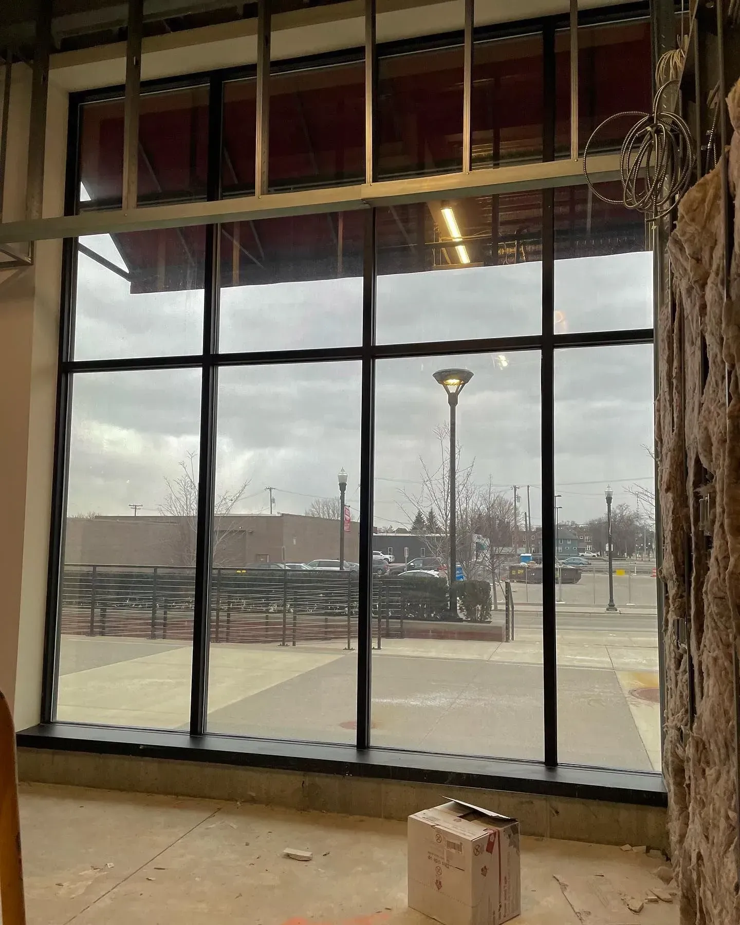 Empty storefront with large windows overlooking a snowy outdoor walkway and lamp post.