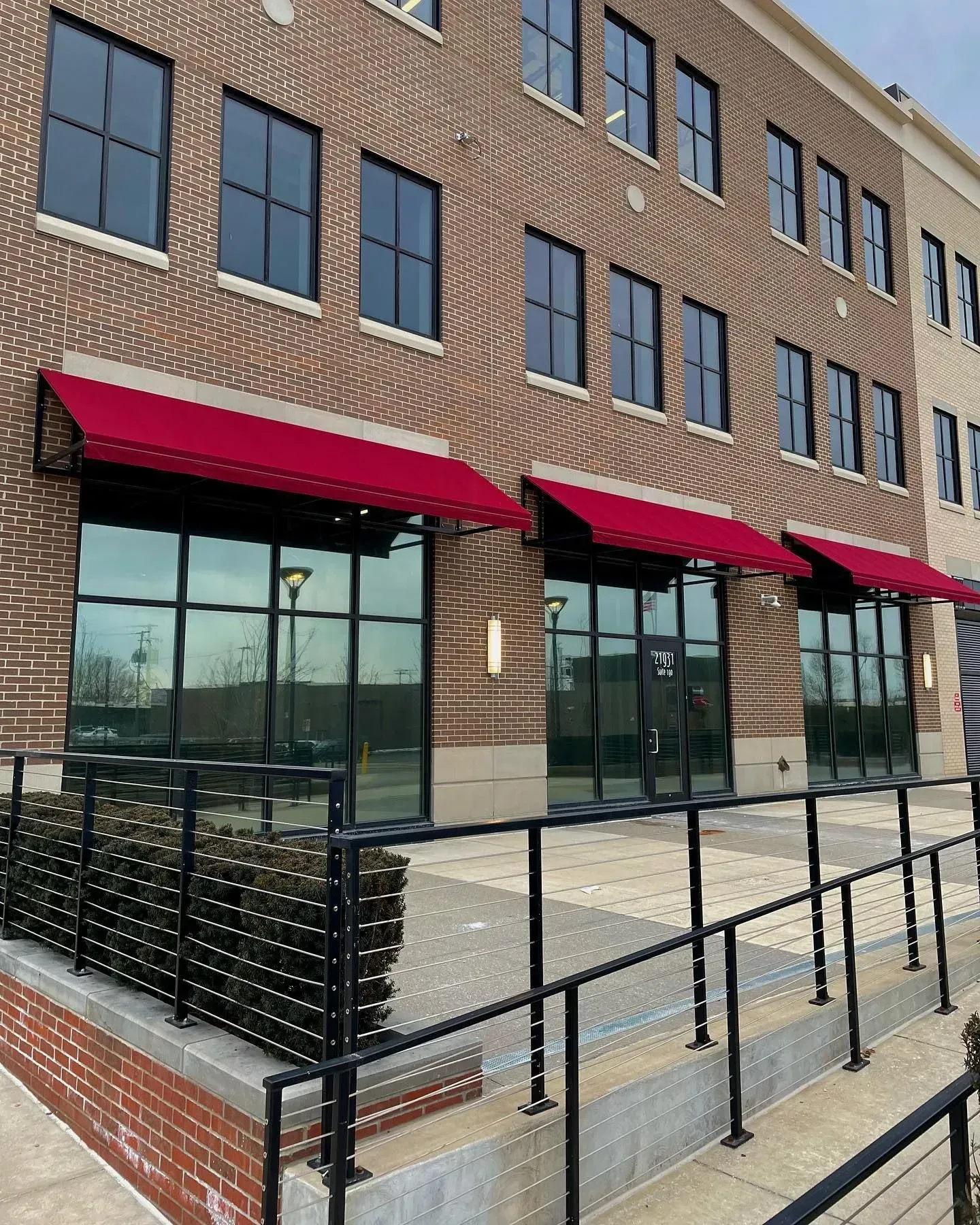 Brick storefront with red awnings and black railings along an accessible sidewalk ramp