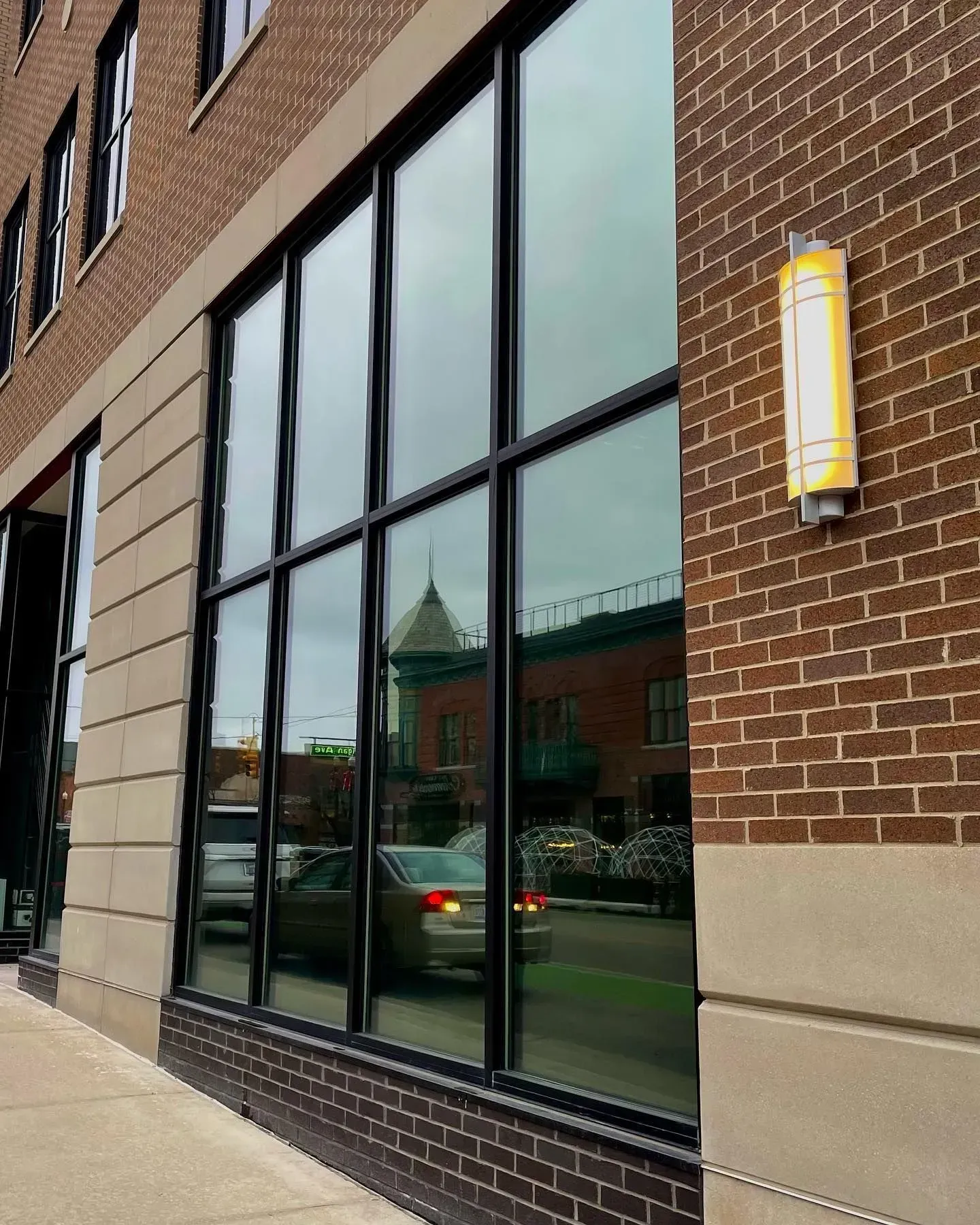 Brick building exterior with large reflective windows and a wall-mounted light fixture