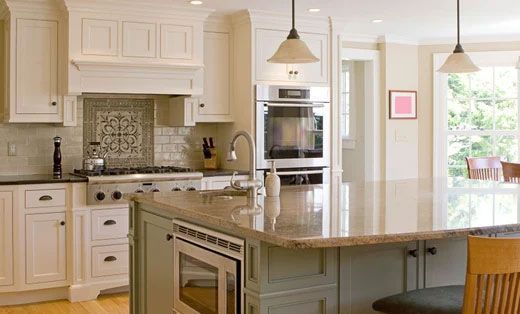 A kitchen with white cabinets , granite counter tops , stainless steel appliances and a large island.