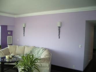 A living room with purple walls and a white couch.