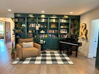 A living room with a chair , piano , and bookshelf.
