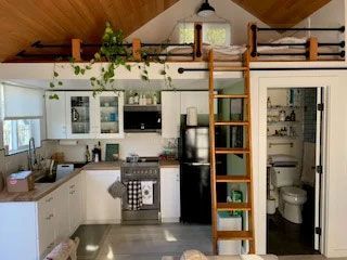 A kitchen with a ladder leading up to a loft bed.