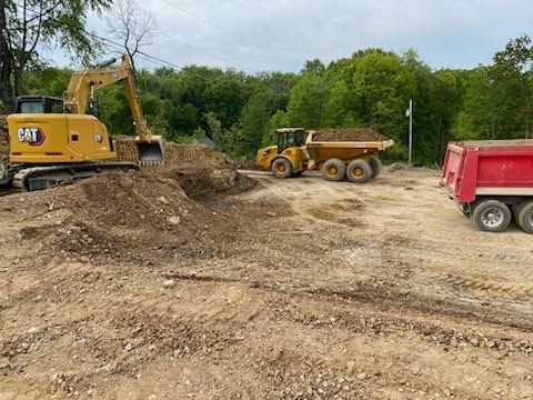 A bulldozer and a dump truck are sitting in a dirt field.