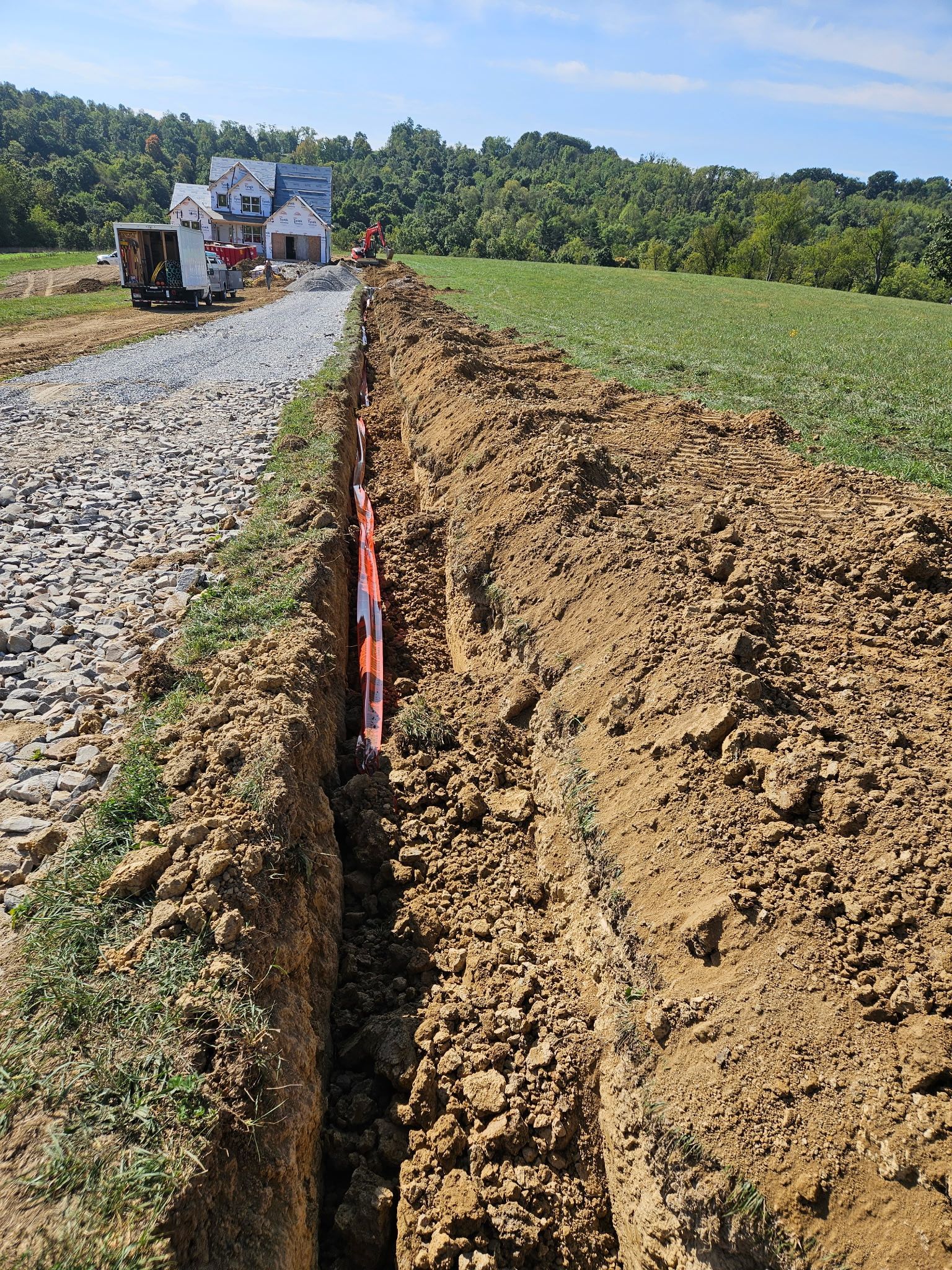 A large trench in the ground with a house in the background.