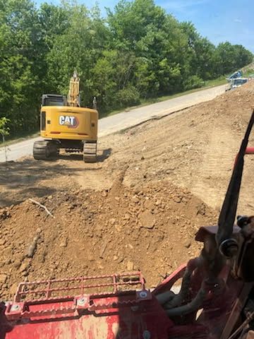 A bulldozer is driving down a dirt road next to a road.