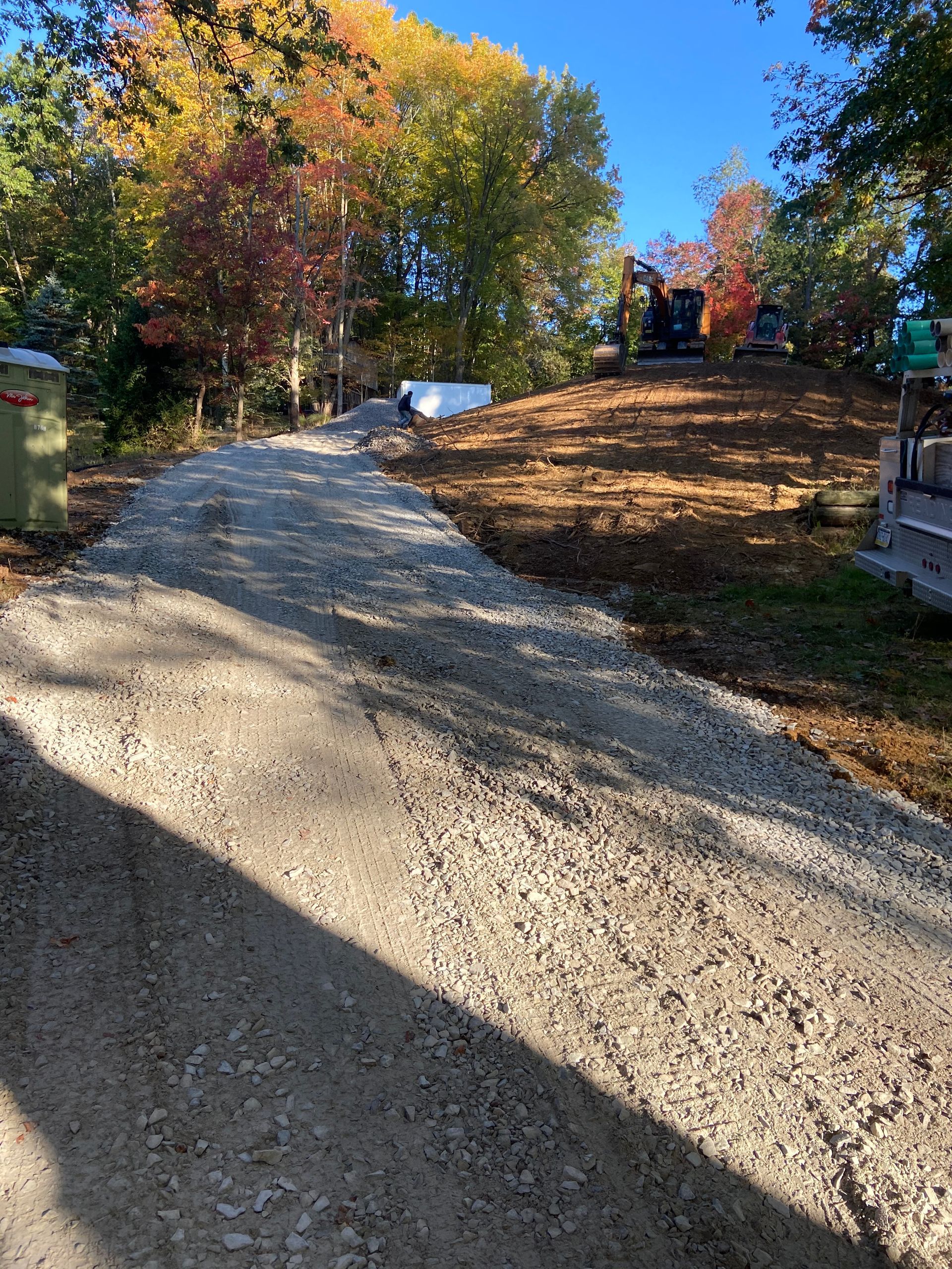 A dirt road with trees on the side of it and a bulldozer in the background.