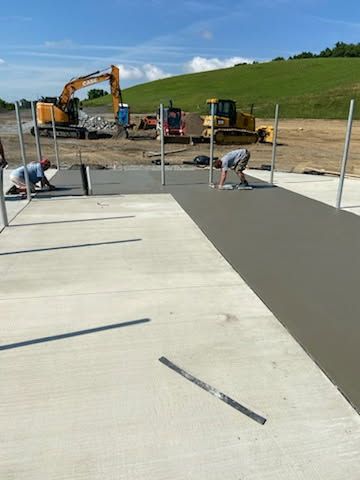 A group of construction workers are working on a concrete driveway.