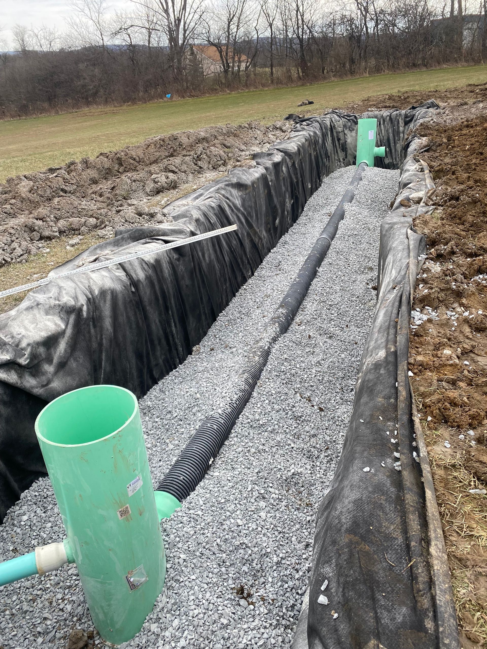 A green pipe is sitting on top of a pile of gravel.