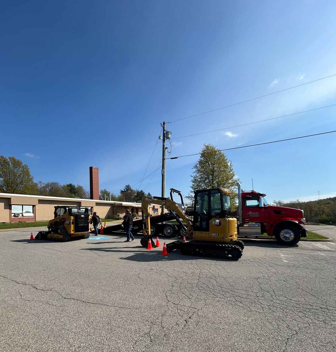A red truck is parked next to a yellow excavator