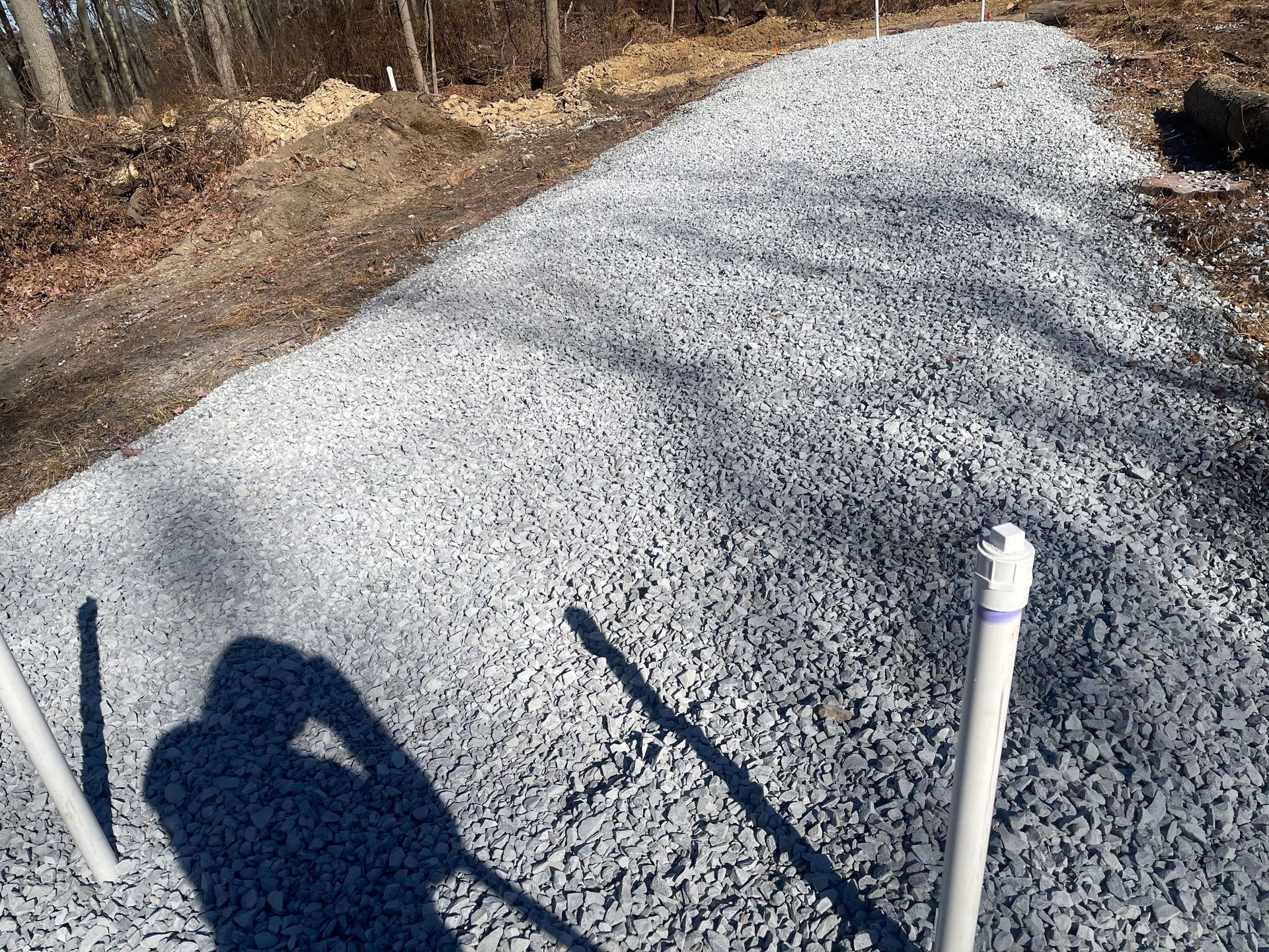 A shadow of a person is cast on a pile of gravel.