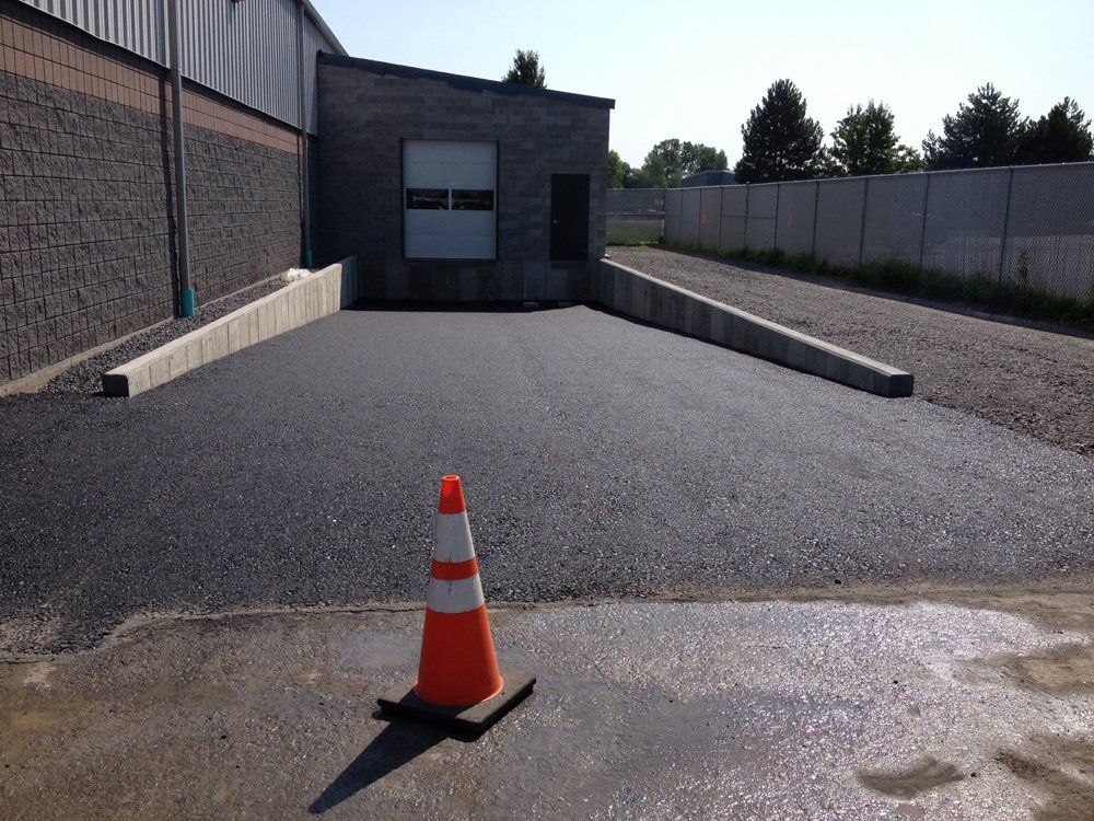 An orange and white traffic cone sits in front of a building