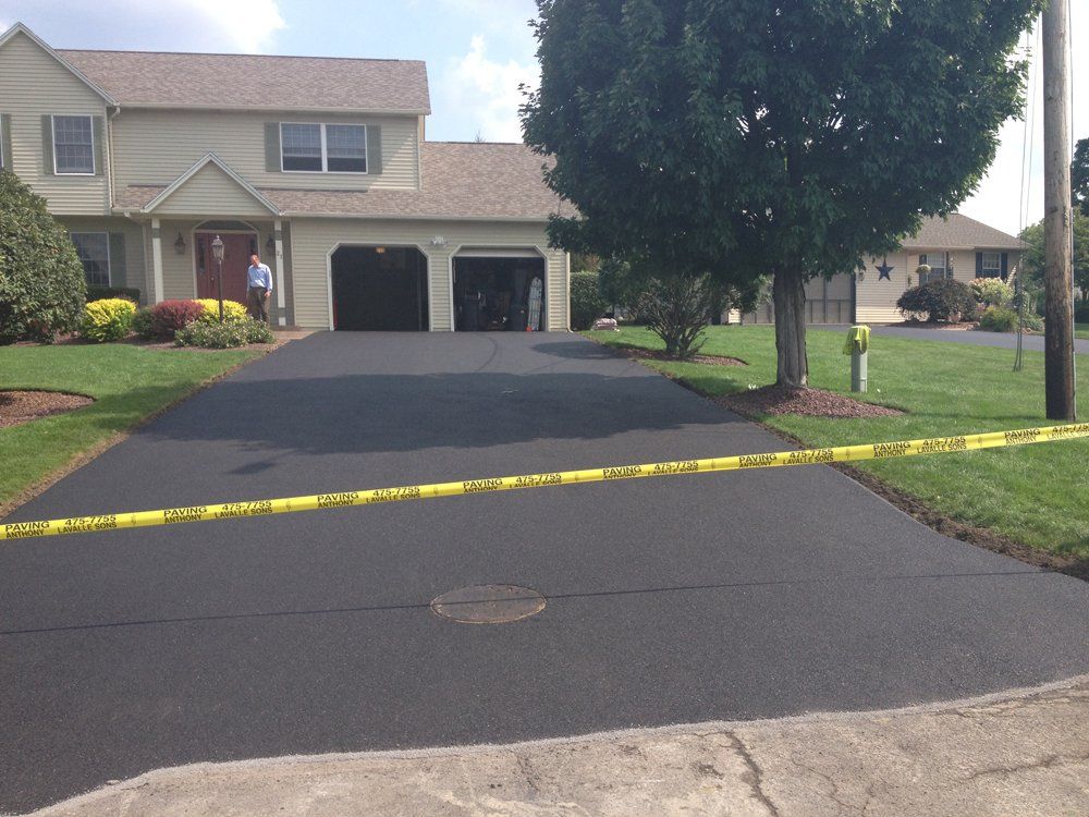 A house with a large driveway and a tree in front of it