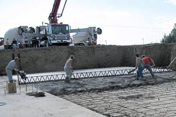 A group of construction workers are working on a concrete floor