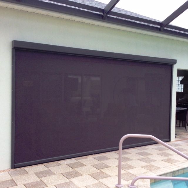 Outdoor roller blind covering a large opening beside a tiled patio
