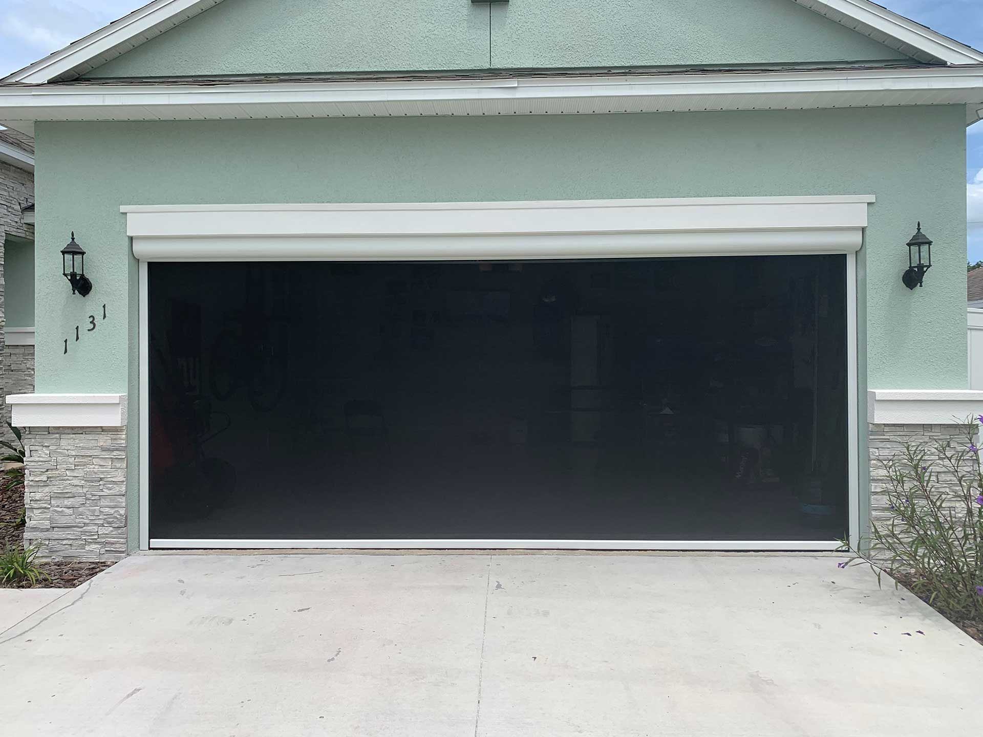 Two-car garage with a large black door and light green exterior front facade