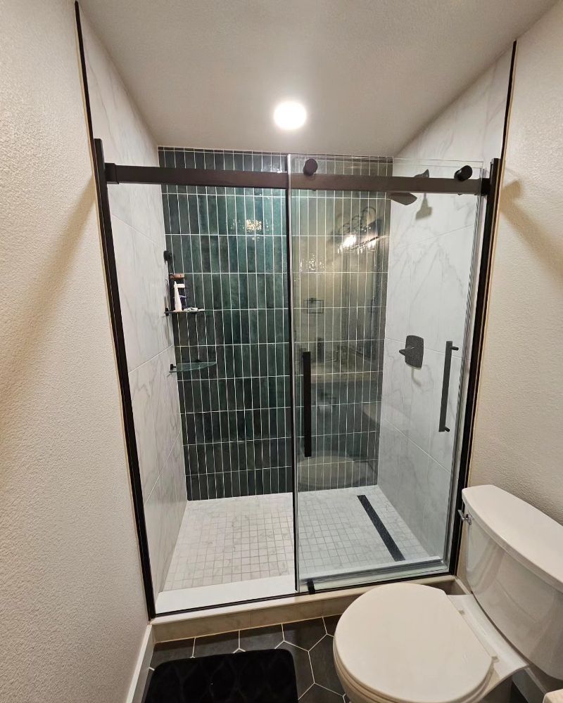 A bathroom with a toilet and a shower with a sliding glass door