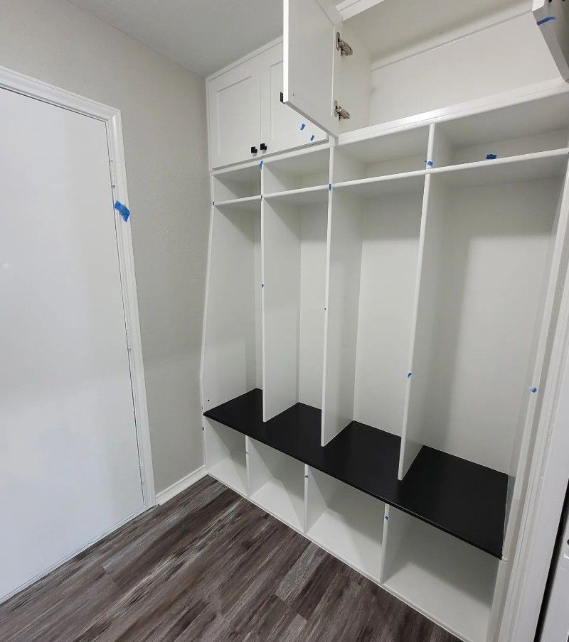 A room with white cabinets and black shelves and a door