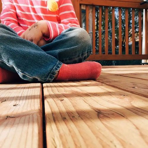 A child is sitting on a wooden deck wearing red socks